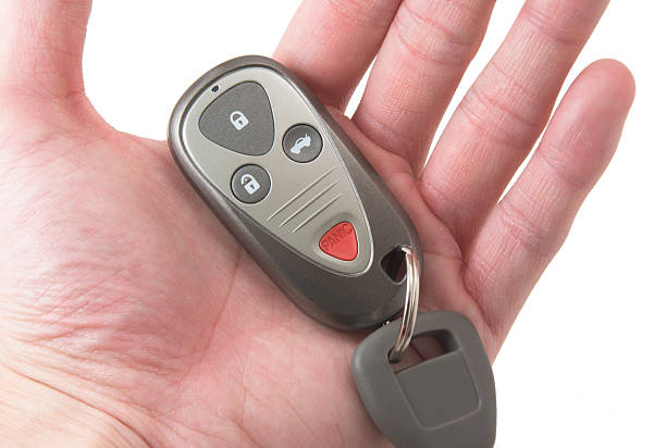 a hand holding car key and remote - alpha locksmith