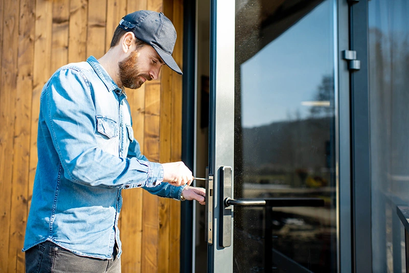 a man with a wearing blue sleeves and a cap is repairing a door key - locksmith services in london
