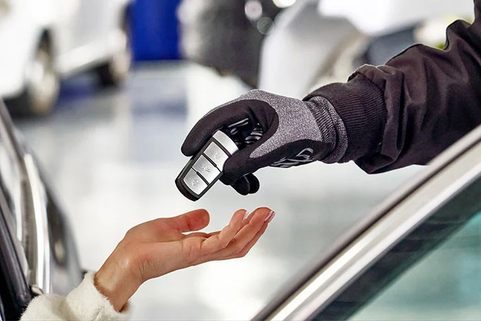 professional car mechanic giving client keys from her repaired car in auto repair service